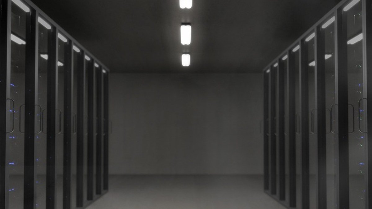 Corridor between rows of dark server racks in a data center, illustrating the computing infrastructure behind the reported OpenAI Google TPU purchase